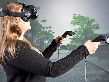 Frau mit VR-Brille und Controllern in der Hand