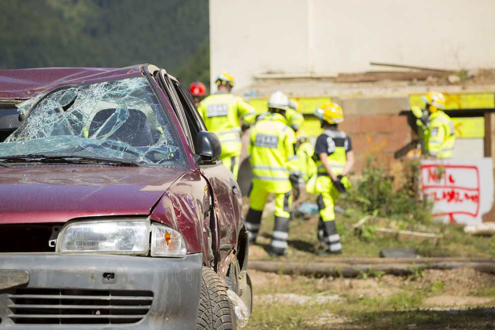 Disaster management trial Eisenerz with a demolated car in the front and frontline helpers in the back 