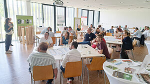 Raum voll mit Zuhörern an Gruppentischen