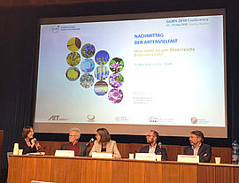 Auf dem Podium: Moderatorin Doris Bauer, Christoph Görg, Gabriele Obermayr, Stephan Pöchtrager, Berhard Föger, dahinter eine laufende Präsentation 