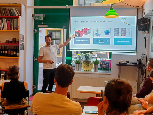 Lukas Bednar beim Pint of Science Festival vor Publikum in einem Lokal, erklärt  Bildverarbeitung am AIT 