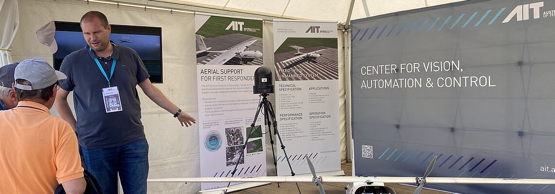 Felix Bruckmüller at the AIT booth talking to a visitor