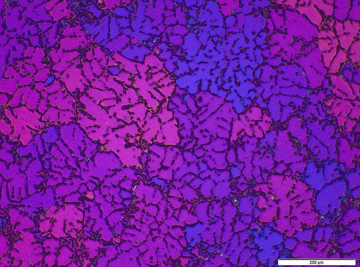 pink und lila eingefärbtes Mikroskopbild einer Metalllegierung 