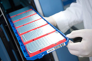 Someone with protective gloves takes a batch of sealed samples from a storage rack