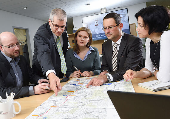  Personen sitzen an einem Tisch und besprechen einen Stadtplan