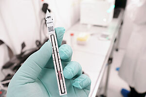 Schnelltest in Hand mit Laborhintergrund
