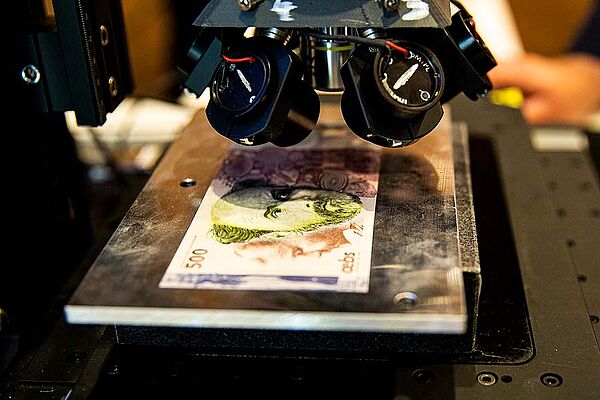 Test banknote on metal plate with different illuminations; inspected with ICI:Microscopy