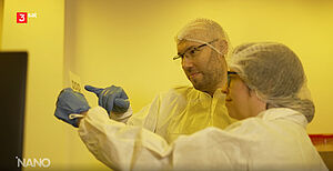 Screenshot der 3Sat Sendung Nano: Zwei Wissenschaftler:innen in einem Reinraum betrachten gedruckte Sensoren.