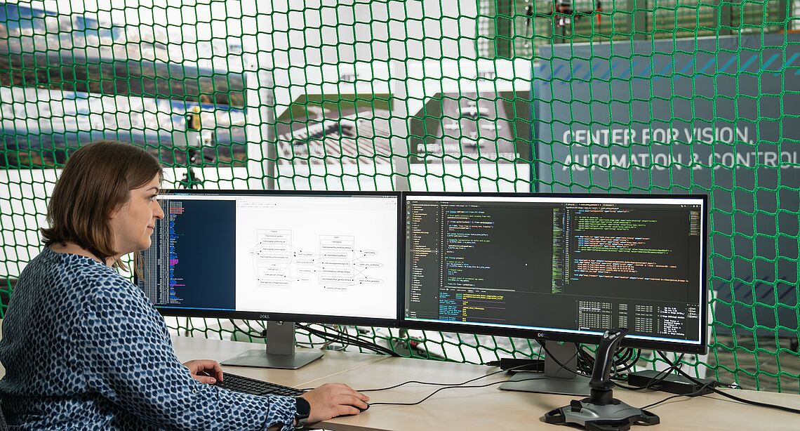 Verena Widhalm programming, in front of her the green safety net of the AIT Aerial Systems Lab