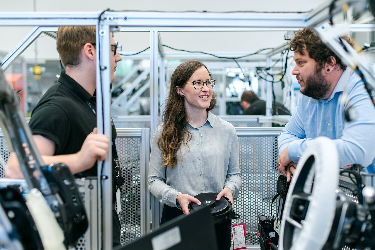 Three people are having a conversation in a big space with technical equipment