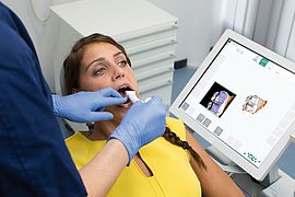 Arzt untersucht die Zähne seiner Patientin mit dem Dentalscanner