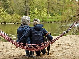 zwei ältere Menschen sitzen vor einem Gewässer