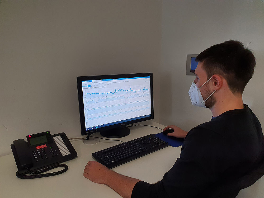 Medizinischer Fachmann vor einem Bildschirm mit Temperaturgraphen