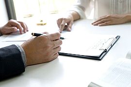 Clipboard is on the table. Two hands can be seen.