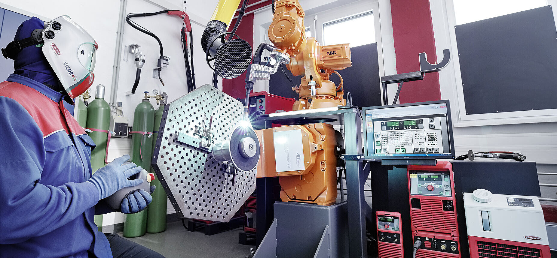 Person sitzt vor der Schweißbrenner-Anlage mit Bauteil