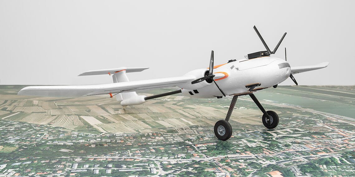 Small model airplane with sensors on the ground on a large aerial photograph in the AIT Aerial Systems Lab