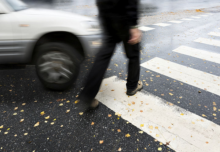 Zebrastreifen mit einem Fußgänger, welcher fast von einem Auto angefahren wird