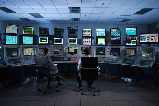 Two people sitting in front of many screens showing important values