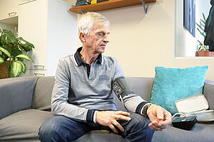 Älterer Mann auf Couch mit Blutdruckmessgerät