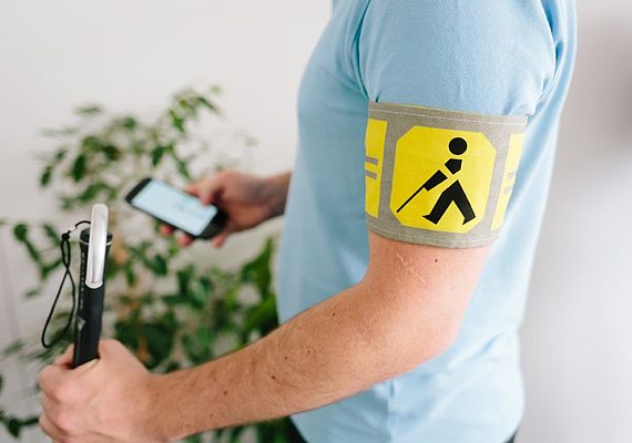 Mann mit Blindenschleife hält Smartphone