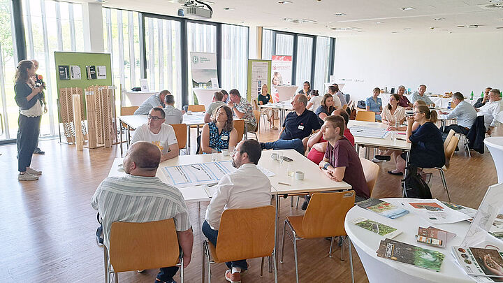 Raum voll mit Zuhörern an Gruppentischen