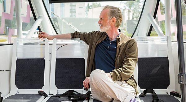 Älterer Mann sitzt in einem öffentlichen Verkehrsmittel
