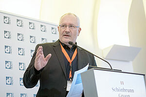 Günter Schreier auf der Bühne vor der dHealth Konferenz Plakatwand