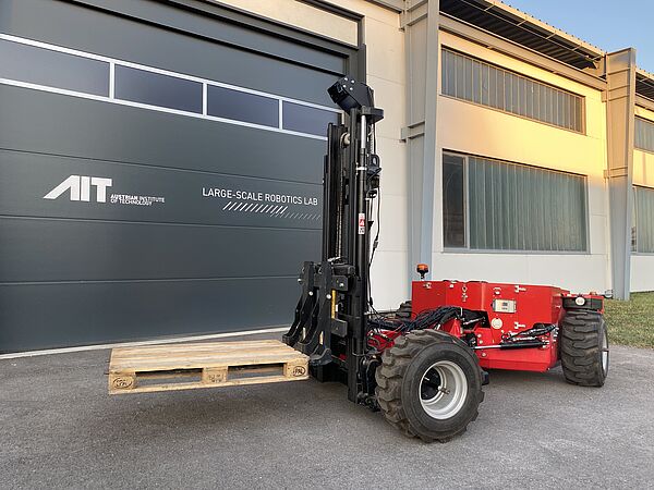 Autonomous forklift truck carrying a pallet in front of the gate of the Large-Scale Robotics Lab