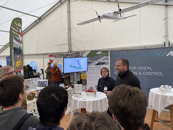 AIT Wissenschaftler F. Bruckmüller am AIT Stand, im Gespräch mit interessierten Besucher:innen am österreichischen Nationalfeiertag