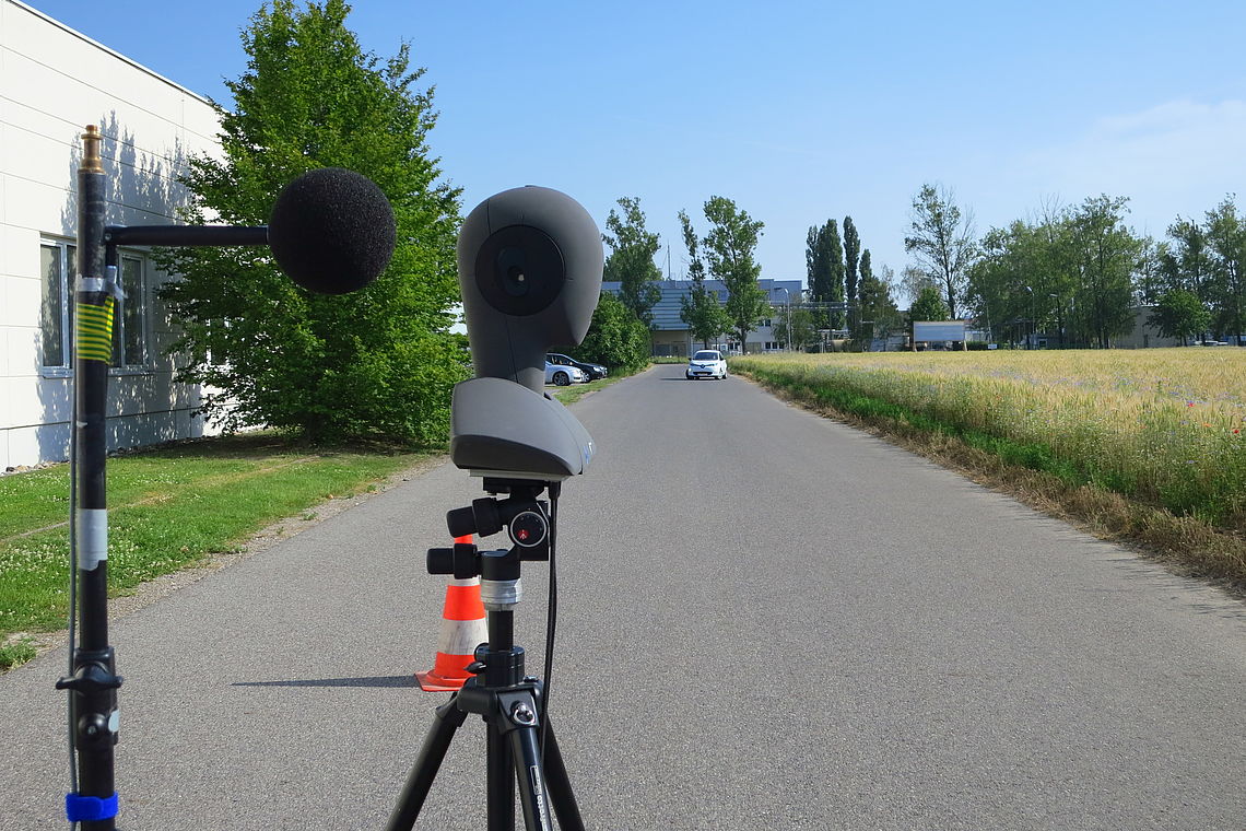 artificial head microphone behind positioned on a road with a car coming closer