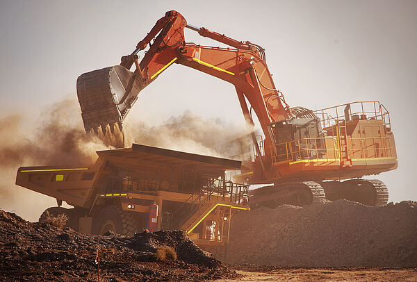 Bagger und LKW auf einer Baustelle mit viel Staub