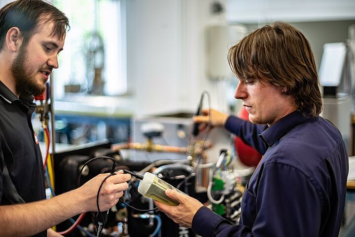 Two persons work on a heat pump