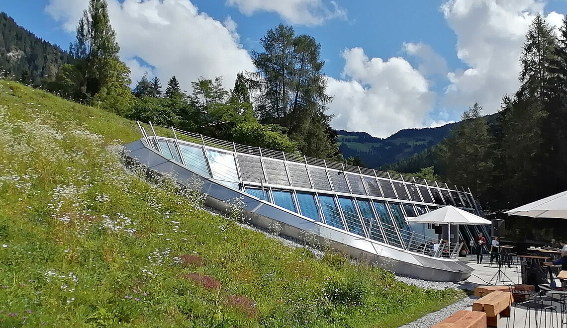 Gebäude mit Glasfront in einem Hügel bedeckt mit grünem Gras