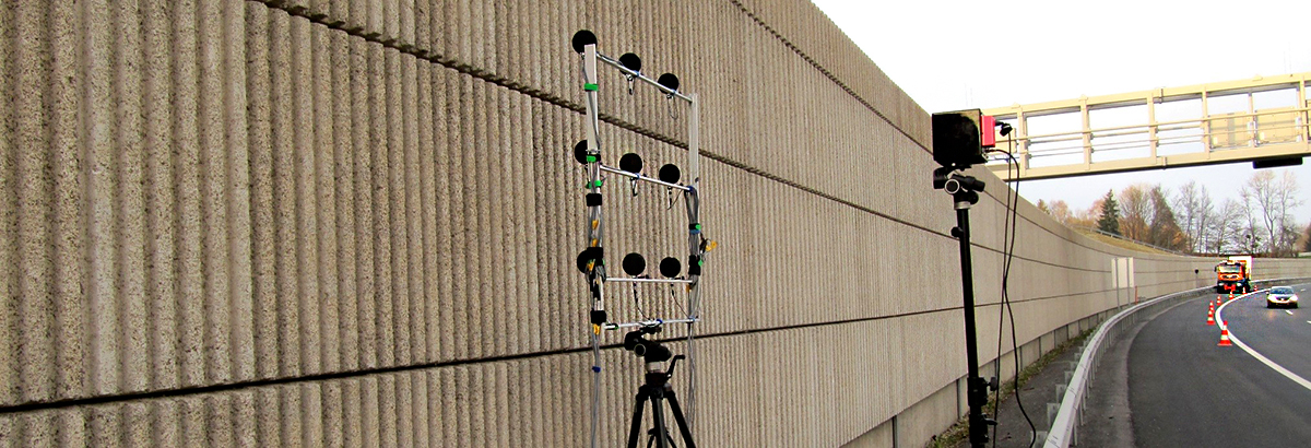 acoustic measuring device is standing in front of a noise barrier at a highway