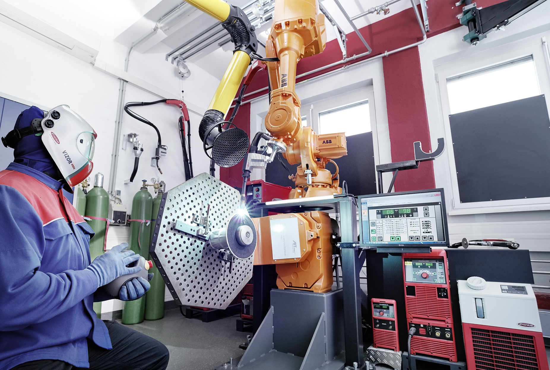 Person sitzt vor der Schweißbrenner-Anlage mit Bauteil