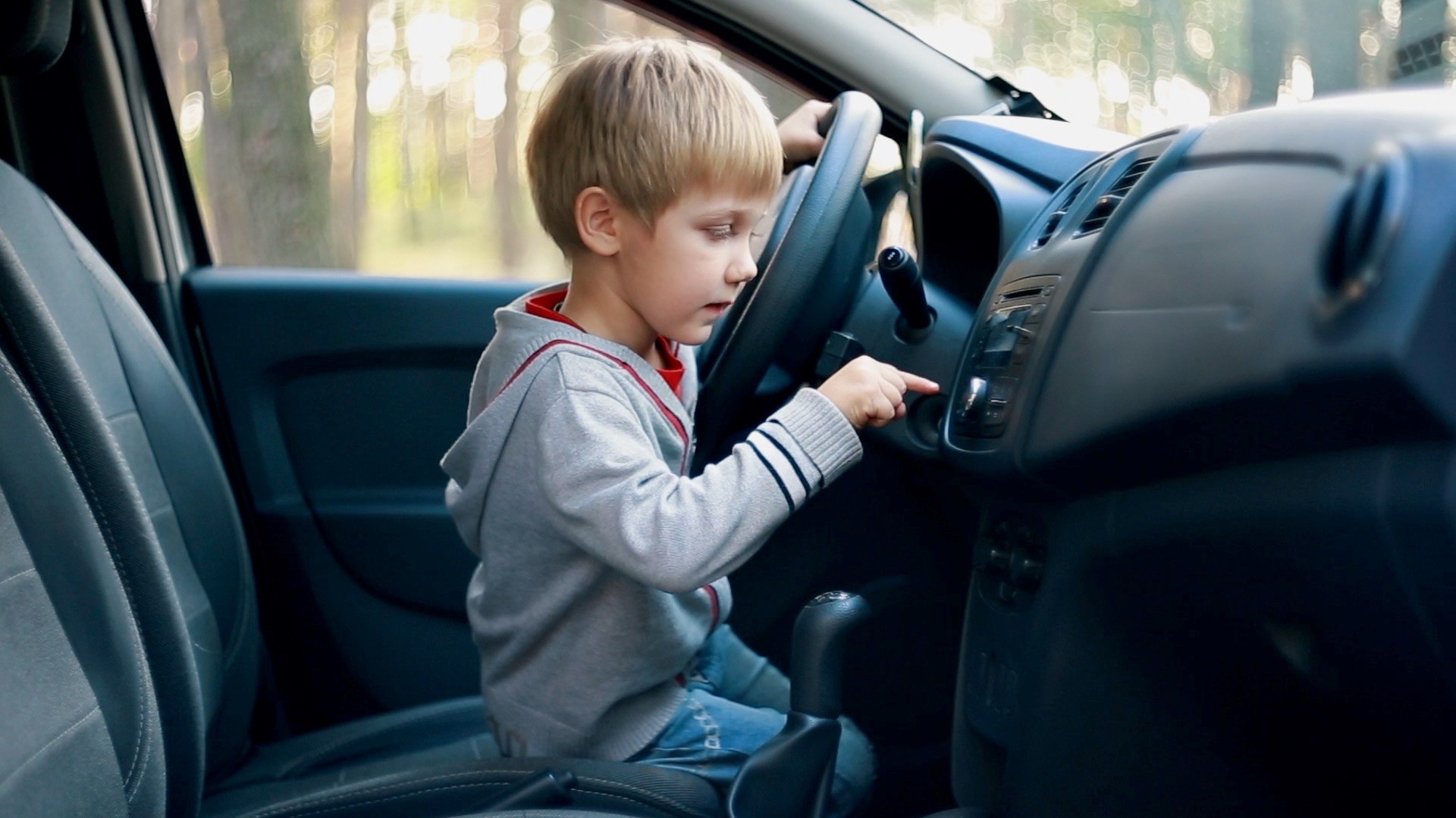 Boy sitting in front of a wheel in the car.