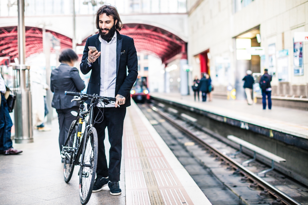 Mann mit Mobiltelefon und Fahrrad, öffentlicher Verkehr