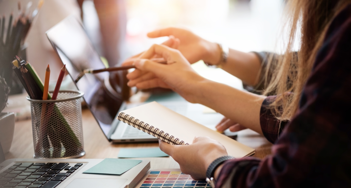 zwei Menschen am Arbeitsplatz auf einen Bildschirm sehend