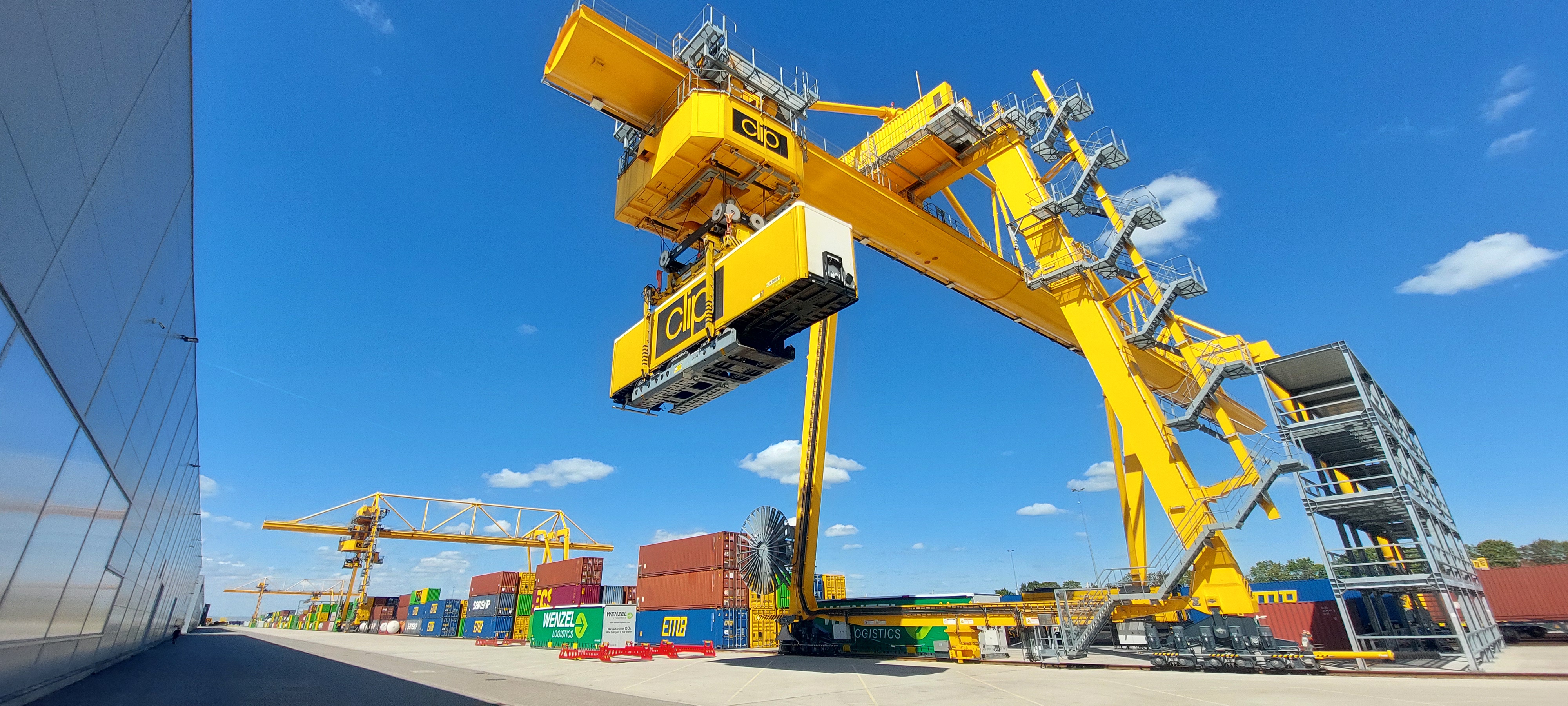 Intermodalkranterminal in gelb, gelber Kran hebt einen gelben Sattelaufleger; Copyright: Künz GmbH