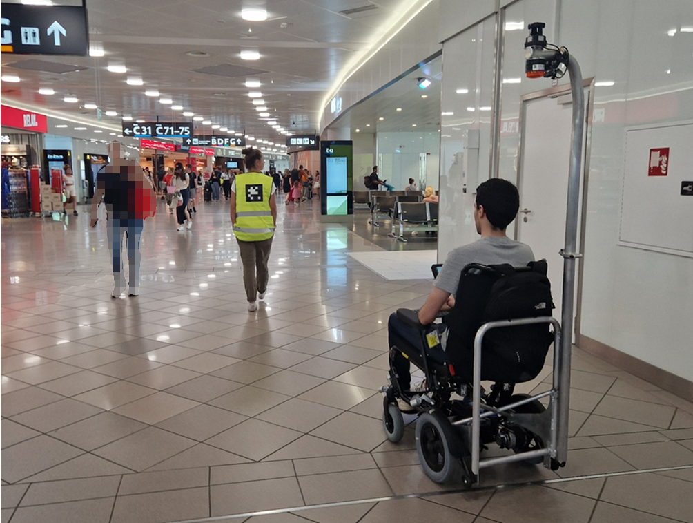 Flughafen Wien, Passagier im Rollstuhl.  Autonom folgt der Rollstuhl einer PRM Assistentin mit Warnweste und Tag 
