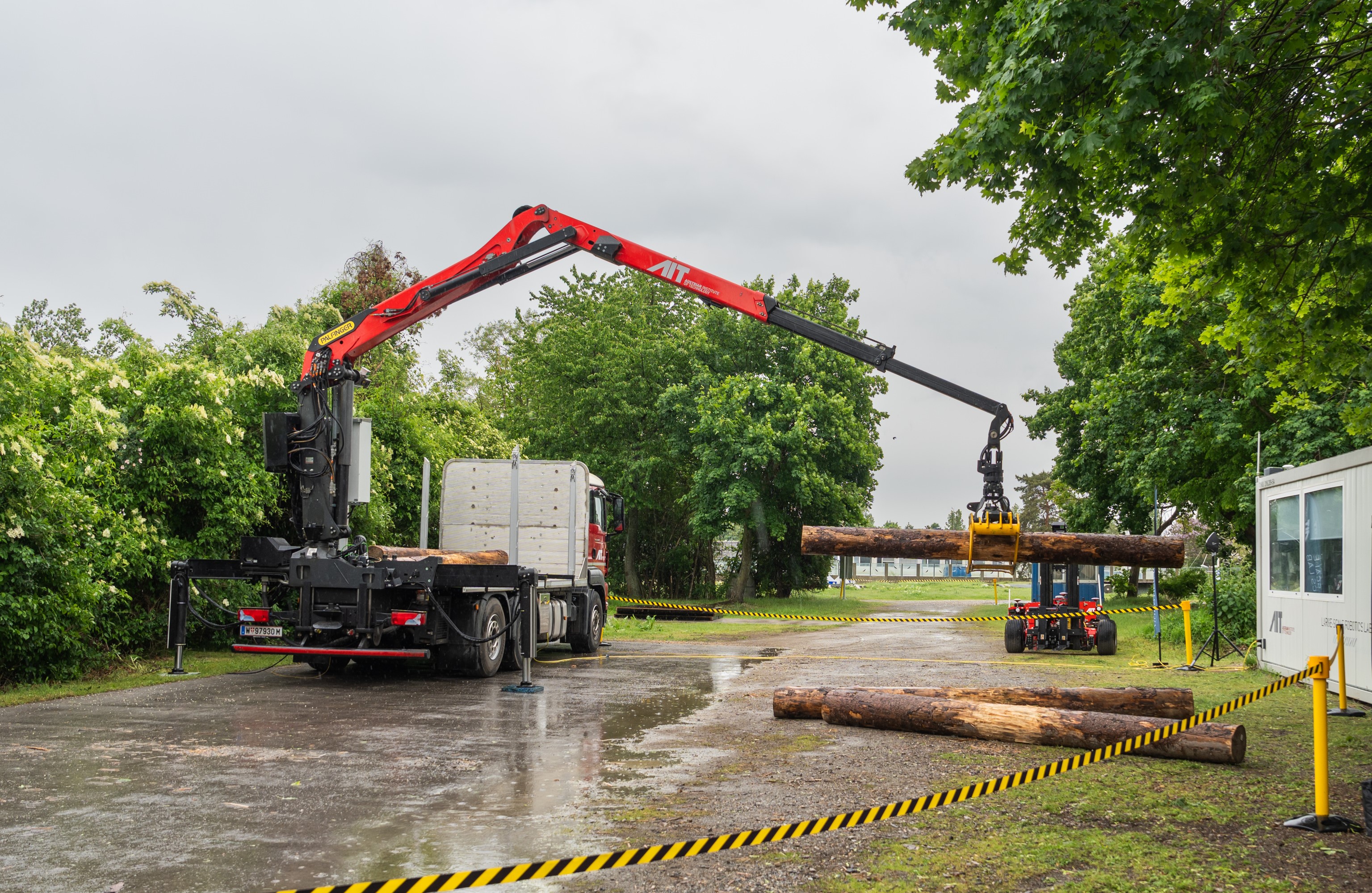 Autonomous forestry crane grabs tree trunk, rainy weather, copyright AIT/TM-Photography