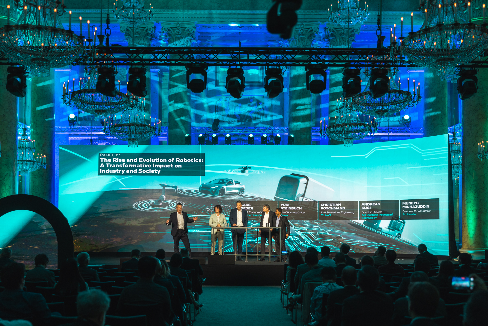 Autonomous Main Event,  Eventhallte -  Experten im Bereich Autonomer Systeme in einer Diskussionsrunde vor blauem Hintergund mit Grafiken. Copyright Christian Steinbrenner