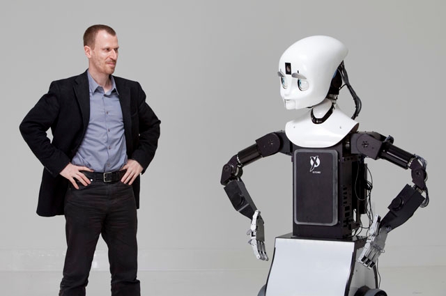 Robotics professor Matthias Scheutz poses for a portrait with his team's robot, "Cindy," in the Human Robot Interaction Lab. Copyright Tufts University 